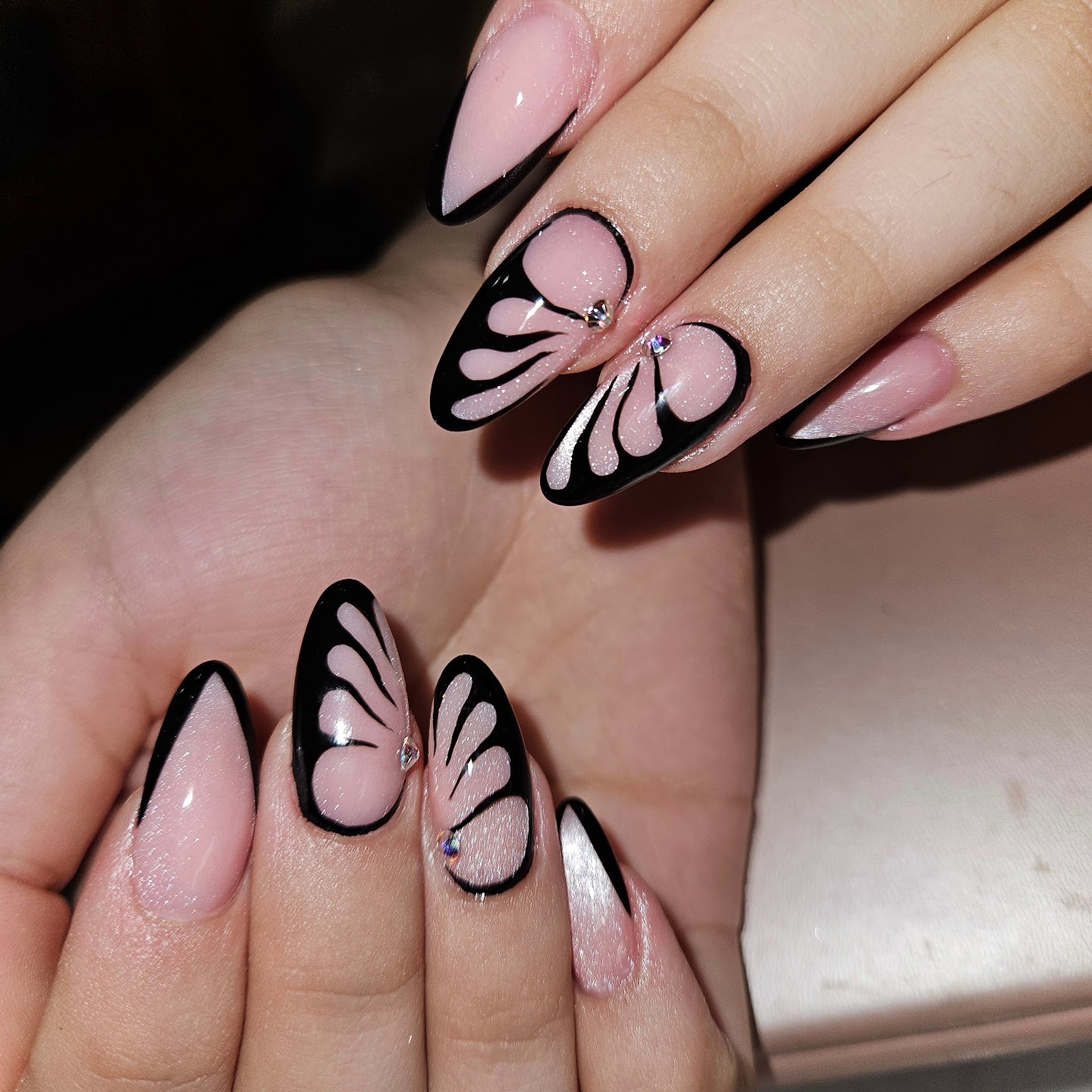 Amandelnagels met zwarte vlinders op een roze basis